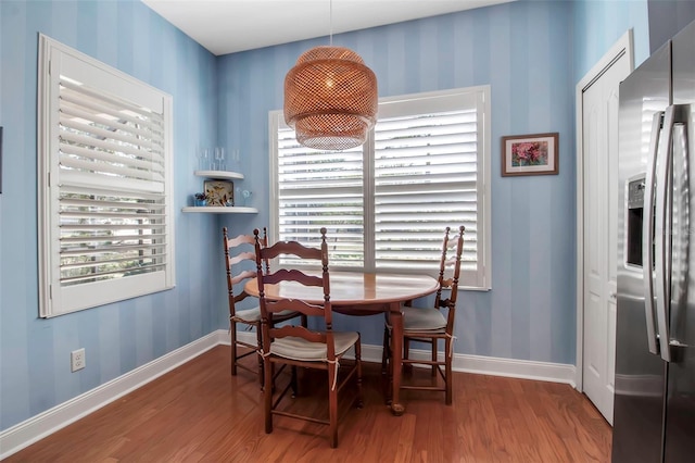 dining area with wood finished floors, baseboards, and wallpapered walls