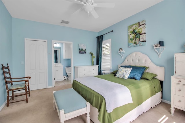 bedroom with light colored carpet, ensuite bathroom, baseboards, ceiling fan, and a closet