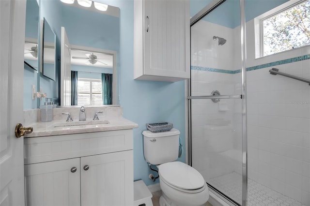 full bathroom with a stall shower, toilet, vanity, and ceiling fan