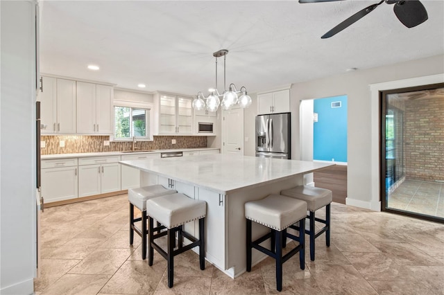 911 Cimarron Cir, Bradenton, FL 34209 - kitchen featuring appliances with stainless steel finishes, decorative backsplash, white cabinets, ceiling fan, and a kitchen breakfast bar