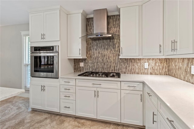 911 Cimarron Cir, Bradenton, FL 34209 - kitchen featuring appliances with stainless steel finishes, wall chimney range hood, light countertops, white cabinetry, and backsplash
