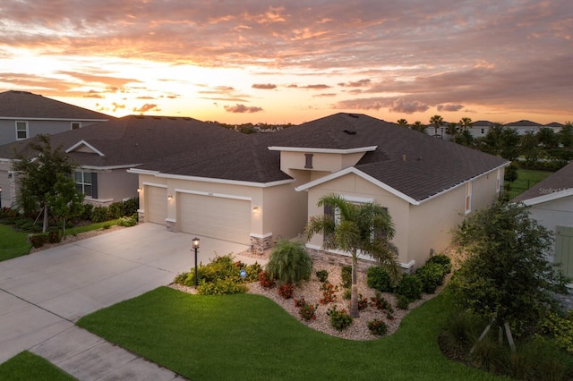 view of front of property with stucco siding, an attached garage, concrete driveway, a yard, and stone siding