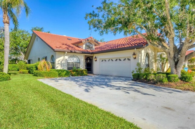 4517 Las Brisas Ln, Sarasota, FL 34238 - mediterranean / spanish house featuring a garage, stucco siding, a tile roof, concrete driveway, and a front yard