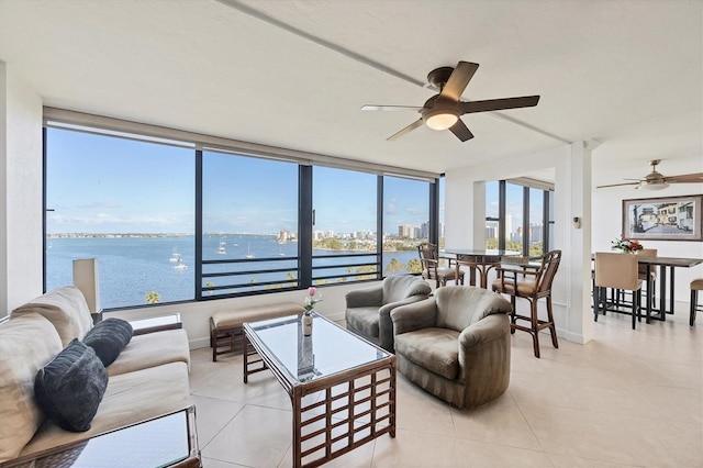 tiled living room with a ceiling fan, plenty of natural light, and a water view