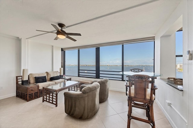 living room featuring ceiling fan, a water view, light tile patterned floors, and baseboards