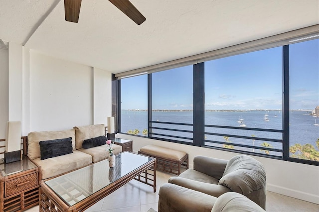 living room featuring a water view, ceiling fan, and tile patterned flooring