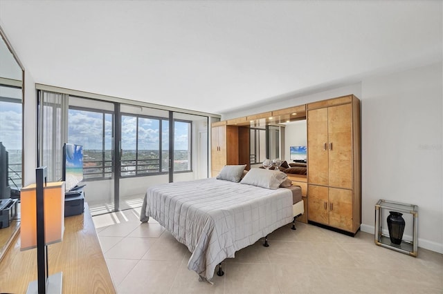 bedroom featuring access to outside, light tile patterned flooring, and baseboards