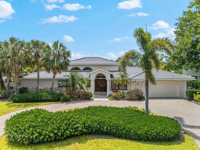 mediterranean / spanish home with decorative driveway, an attached garage, and stucco siding