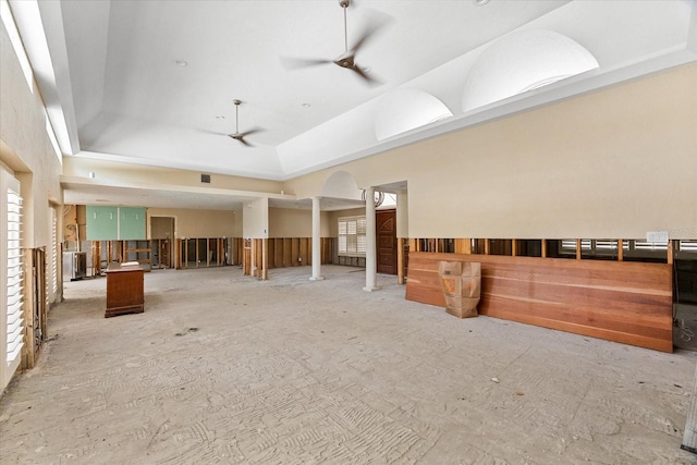 misc room featuring ceiling fan, a tray ceiling, and arched walkways