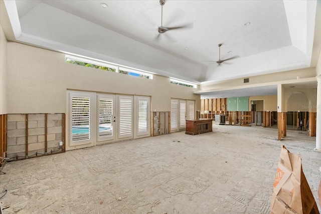 misc room with a ceiling fan, a tray ceiling, and a high ceiling