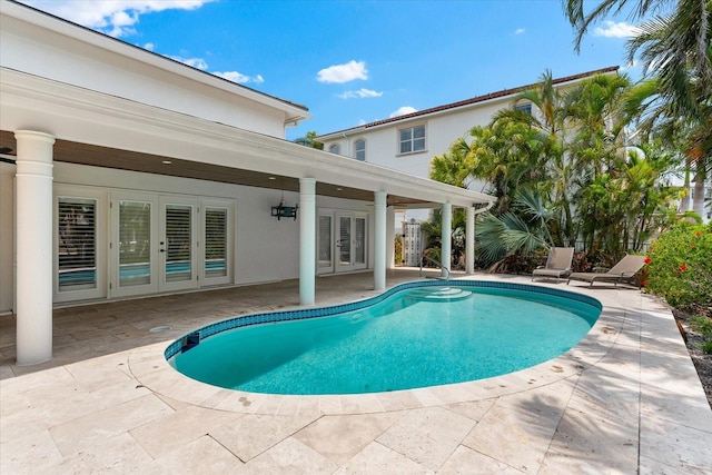 outdoor pool with french doors and a patio area