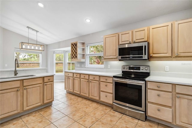 kitchen featuring appliances with stainless steel finishes, light brown cabinets, a sink, vaulted ceiling, and light countertops