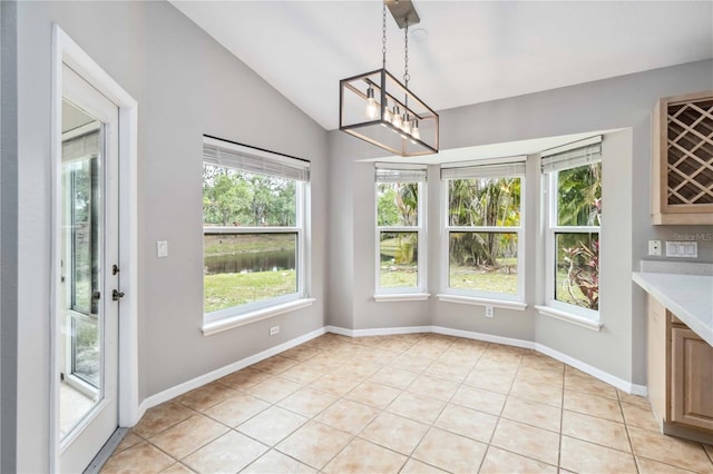 unfurnished dining area featuring vaulted ceiling, a chandelier, light tile patterned floors, and baseboards