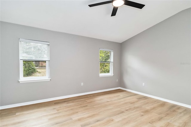 spare room featuring light wood-style flooring, ceiling fan, lofted ceiling, and baseboards