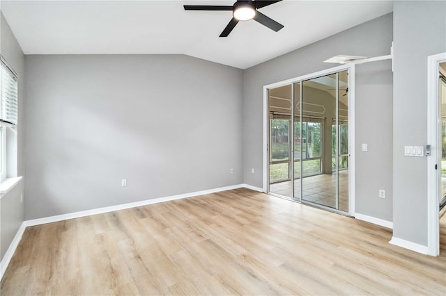 unfurnished room with plenty of natural light, wood finished floors, a ceiling fan, vaulted ceiling, and baseboards