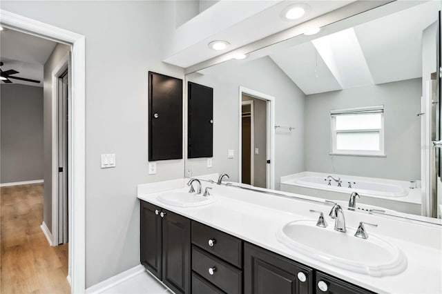 full bath with a bath, lofted ceiling, wood finished floors, double vanity, and baseboards