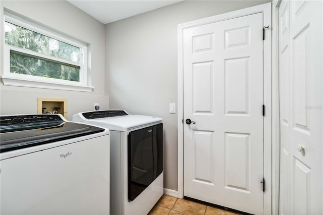 clothes washing area with washing machine and clothes dryer, light tile patterned floors, and baseboards
