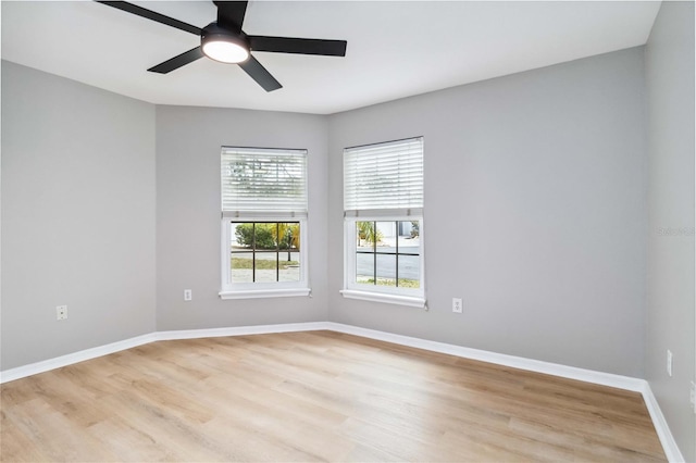 empty room featuring light wood-type flooring, a ceiling fan, and baseboards