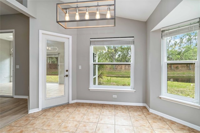doorway to outside featuring plenty of natural light, lofted ceiling, and baseboards