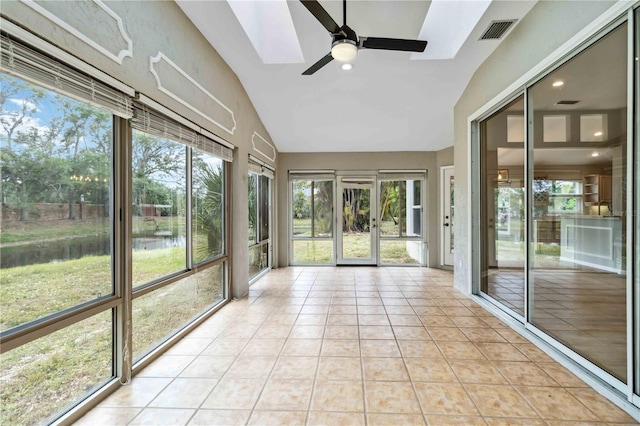 unfurnished sunroom with plenty of natural light, a skylight, a water view, tile patterned flooring, and high vaulted ceiling