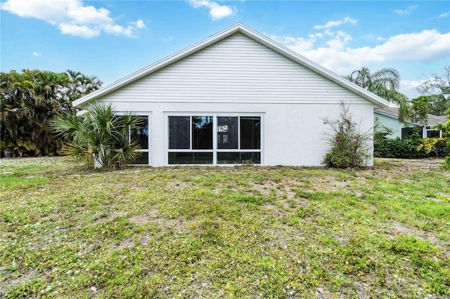 back of property with a yard and stucco siding