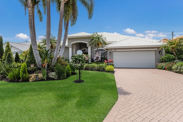 3806 72nd Ter E, Sarasota, FL 34243 - mediterranean / spanish-style house featuring a garage, a front yard, decorative driveway, and stucco siding