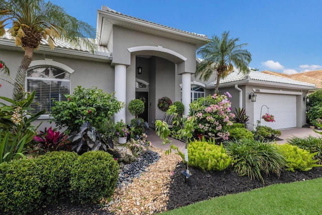 3806 72nd Ter E, Sarasota, FL 34243 - view of front of house with stucco siding, an attached garage, a tile roof, and driveway