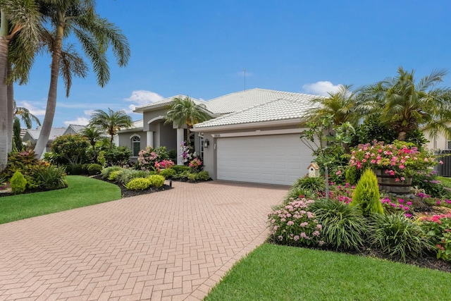 3806 72nd Ter E, Sarasota, FL 34243 - mediterranean / spanish house featuring an attached garage, decorative driveway, stucco siding, and a tile roof