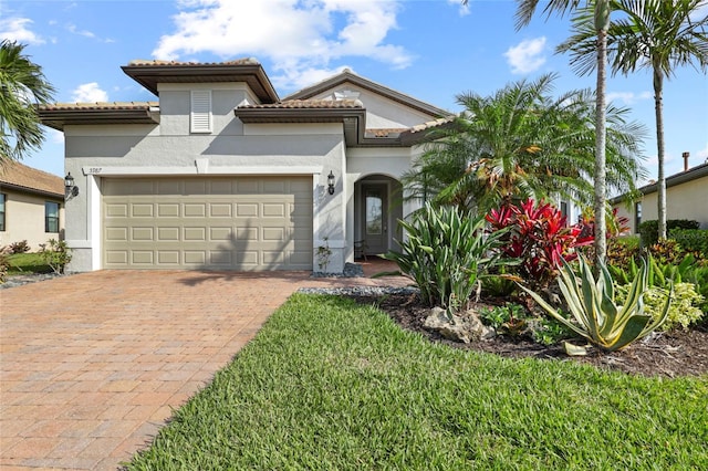 mediterranean / spanish home featuring stucco siding, an attached garage, decorative driveway, and a tiled roof
