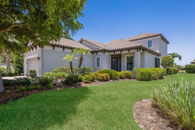 8191 Gabanna Dr, Sarasota, FL 34231 - back of property featuring a tile roof, an attached garage, a lawn, and stucco siding