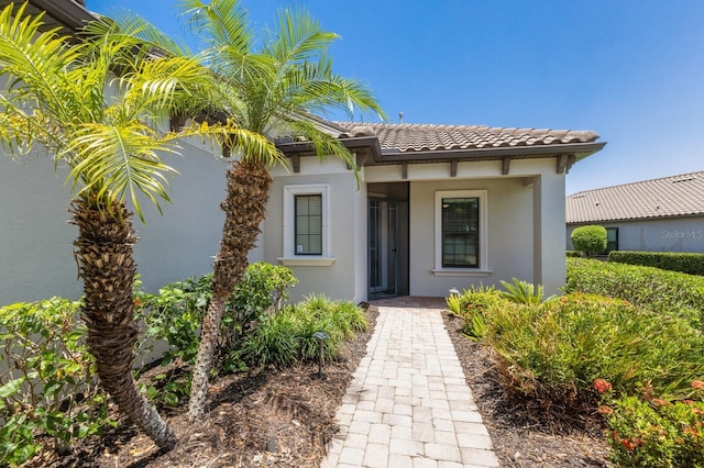 8191 Gabanna Dr, Sarasota, FL 34231 - view of exterior entry with a tile roof and stucco siding