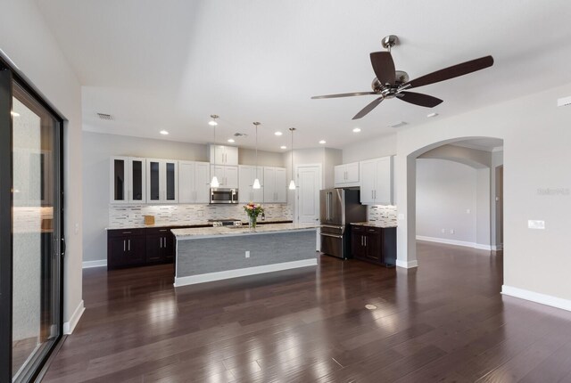 8191 Gabanna Dr, Sarasota, FL 34231 - kitchen featuring appliances with stainless steel finishes, arched walkways, backsplash, white cabinetry, and recessed lighting