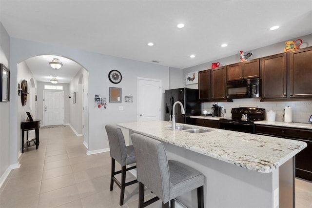 5111 11th St E, Bradenton, FL 34203 - kitchen featuring black appliances, a sink, arched walkways, a kitchen breakfast bar, and backsplash