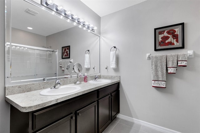 5111 11th St E, Bradenton, FL 34203 - full bathroom with tile patterned floors, a shower with shower door, double vanity, and baseboards
