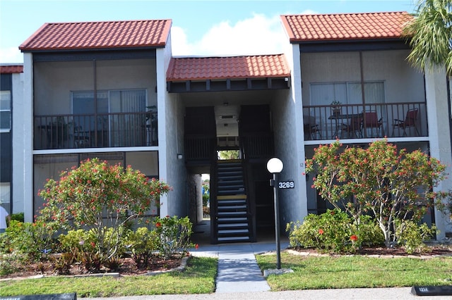 view of front of house with a tiled roof, stairs, and stucco siding