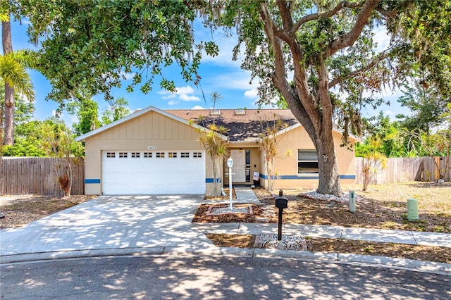 ranch-style home featuring an attached garage, fence, concrete driveway, and roof with shingles