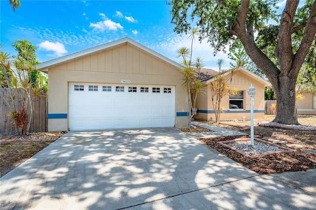 single story home featuring concrete driveway, stucco siding, fence, and an attached garage