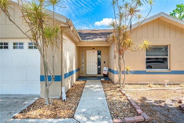 view of exterior entry with an attached garage and stucco siding