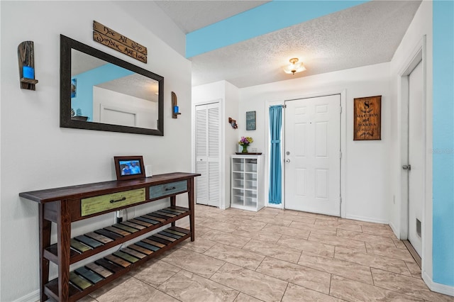foyer entrance with baseboards and a textured ceiling