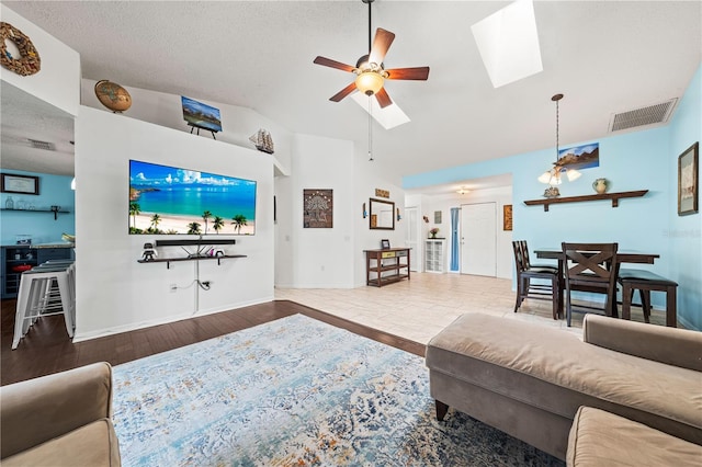 living area with a skylight, a ceiling fan, wood finished floors, lofted ceiling, and baseboards