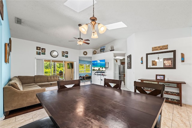 dining room featuring a skylight, lofted ceiling, ceiling fan, and a textured ceiling