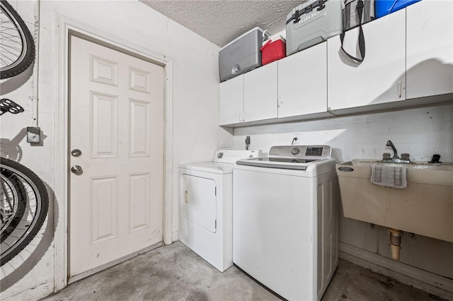 clothes washing area featuring cabinet space, separate washer and dryer, and a textured ceiling