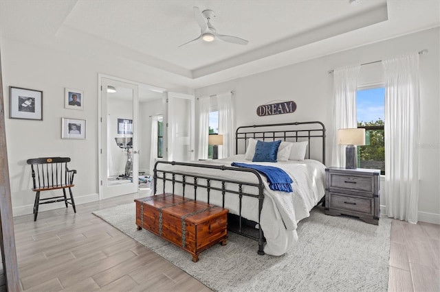 5823 Title Row Dr, Bradenton, FL 34210 - bedroom featuring a raised ceiling, multiple windows, and light wood-style floors