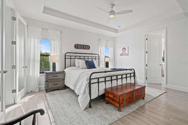 5823 Title Row Dr, Bradenton, FL 34210 - bedroom with a raised ceiling, multiple windows, light wood finished floors, and a ceiling fan