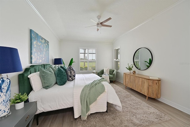 bedroom featuring ornamental molding, wood finished floors, baseboards, ceiling fan, and a textured ceiling