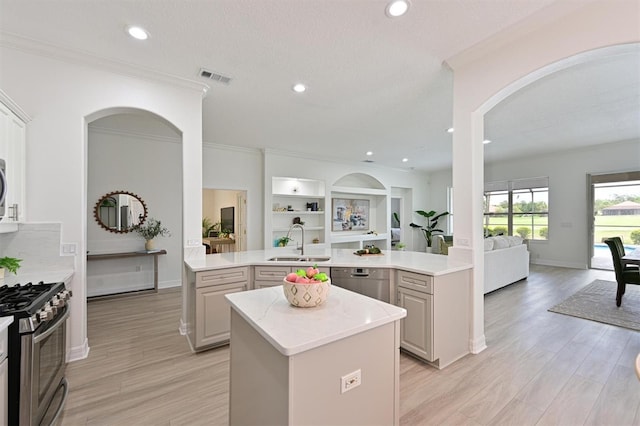 kitchen with open floor plan, stainless steel appliances, a kitchen island, a sink, and arched walkways