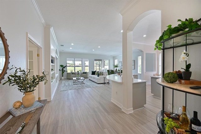 kitchen with arched walkways, light countertops, ornamental molding, light wood-style flooring, and recessed lighting