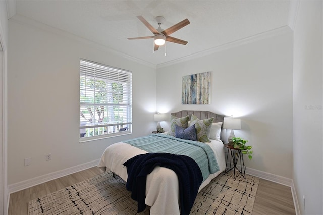 bedroom with ornamental molding, light wood finished floors, baseboards, and a ceiling fan