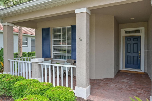 view of exterior entry featuring covered porch and stucco siding