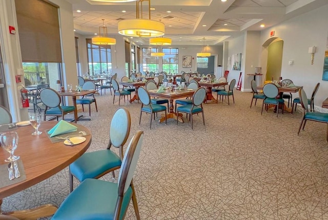 carpeted dining space featuring coffered ceiling, arched walkways, recessed lighting, and baseboards